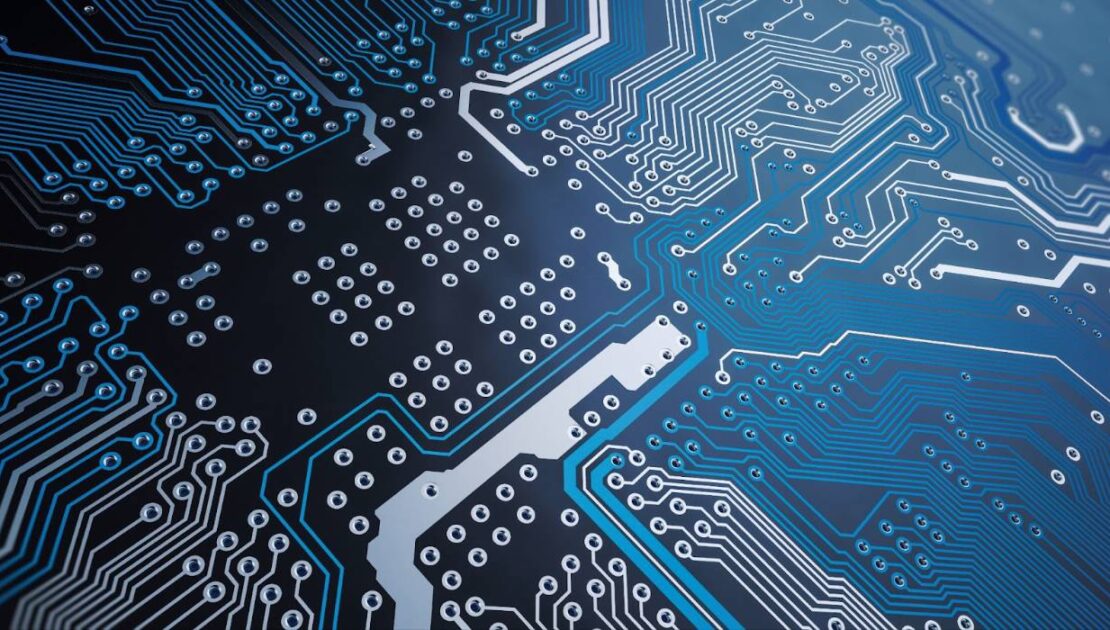 Close-up view of a detailed electronic circuit board with interconnected pathways and components, featuring blue and silver lines on a dark background.