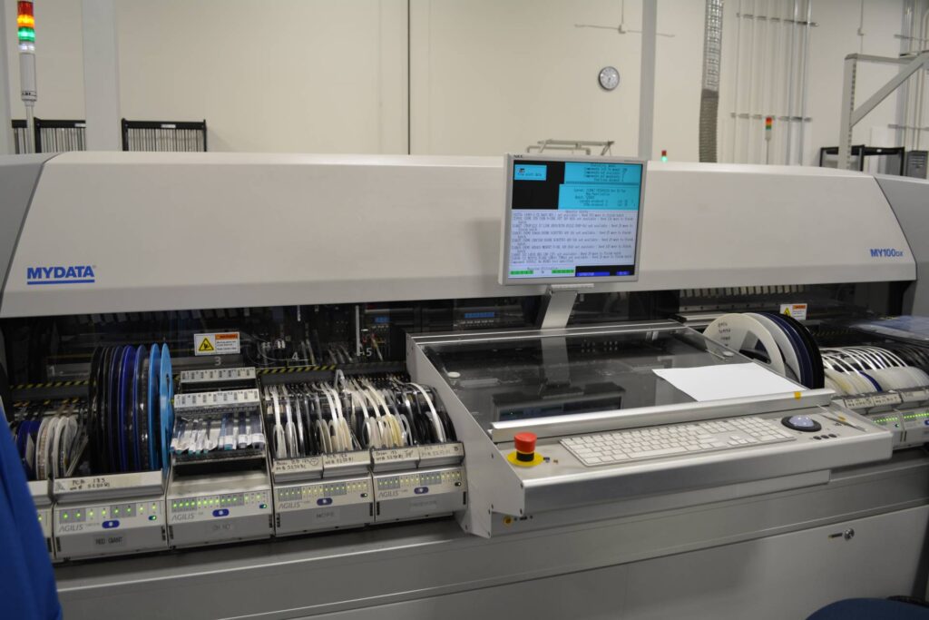 Automated pick-and-place machine used in surface mount technology (SMT) placing electronic components onto a PCB during high-speed assembly.