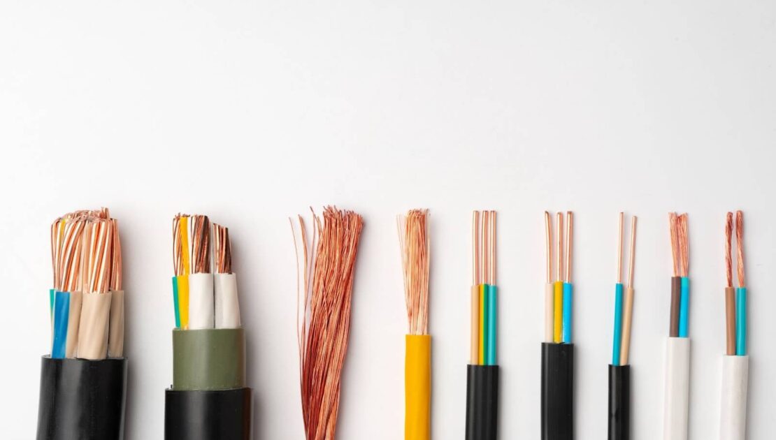 Assorted electrical copper wires with different thicknesses and insulation colors arranged in a row on a white background.