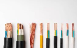 Assorted electrical copper wires with different thicknesses and insulation colors arranged in a row on a white background.