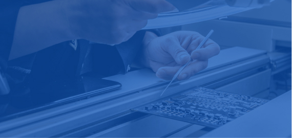 A blue-toned close-up of a person's hand writing with a pen on a document next to a keyboard, suggesting an office or signing setting.