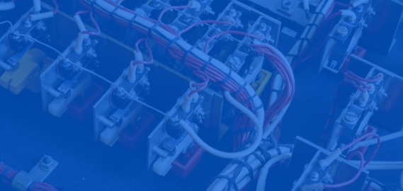 Bundled red and white wires routed across rows of electrical relays in a control panel.