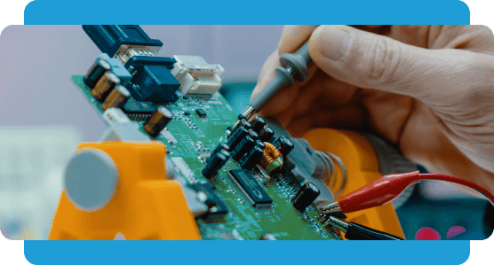 Hand holding a test probe against a green circuit board clamped in an orange stand.